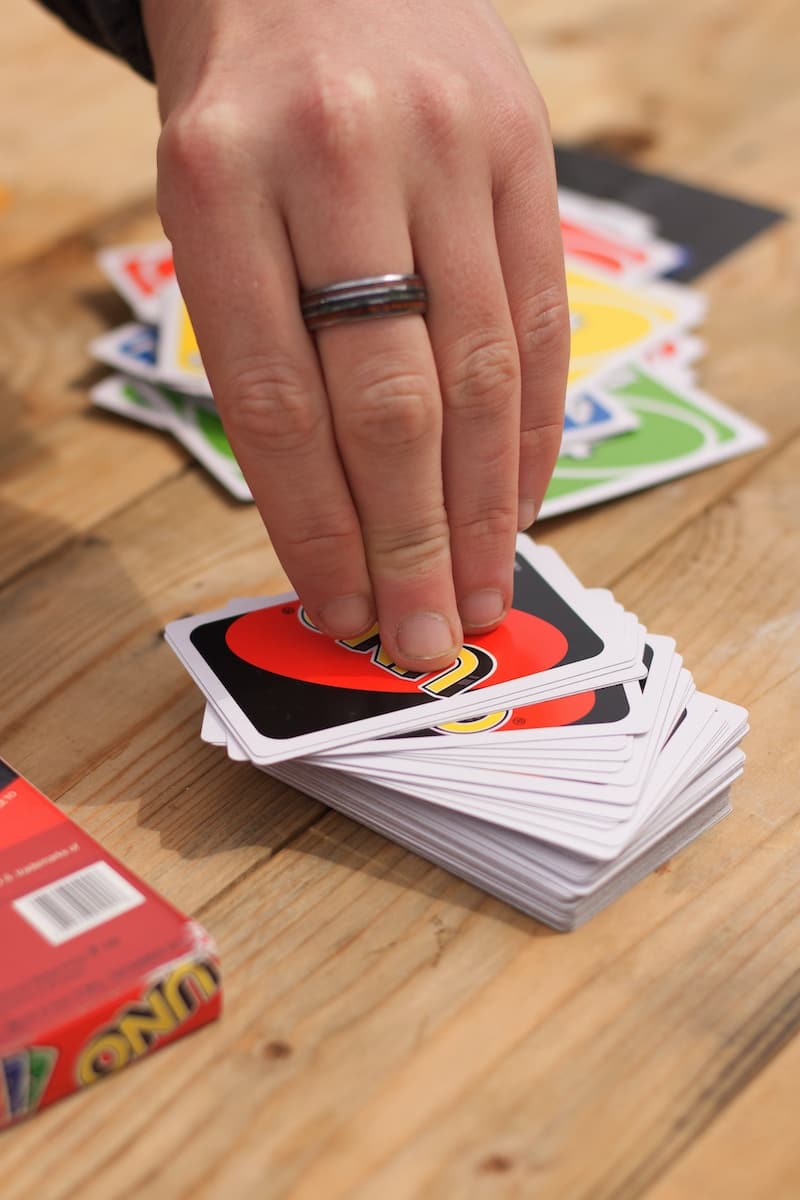 person wearing silver ring picking an Uno card