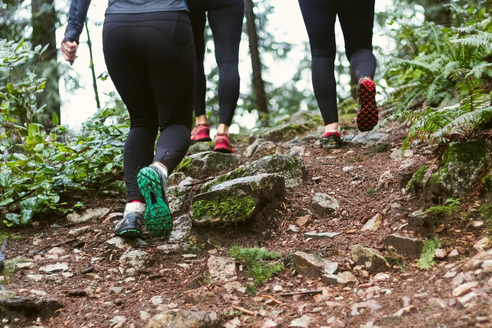 person in black leggings and green sneakers hiking
